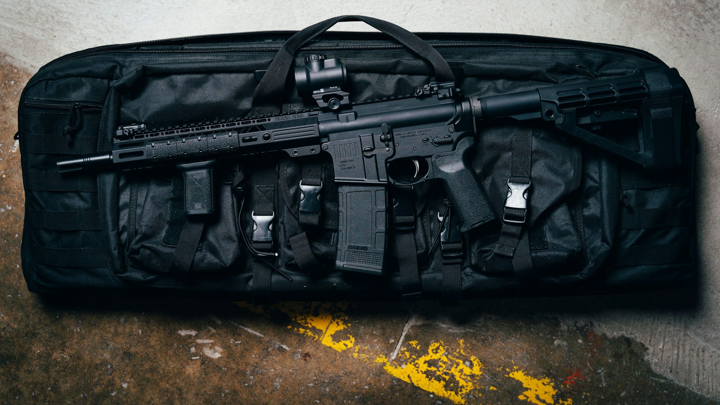 AR-15 rifle laying on a carry bag on a parking garage floor